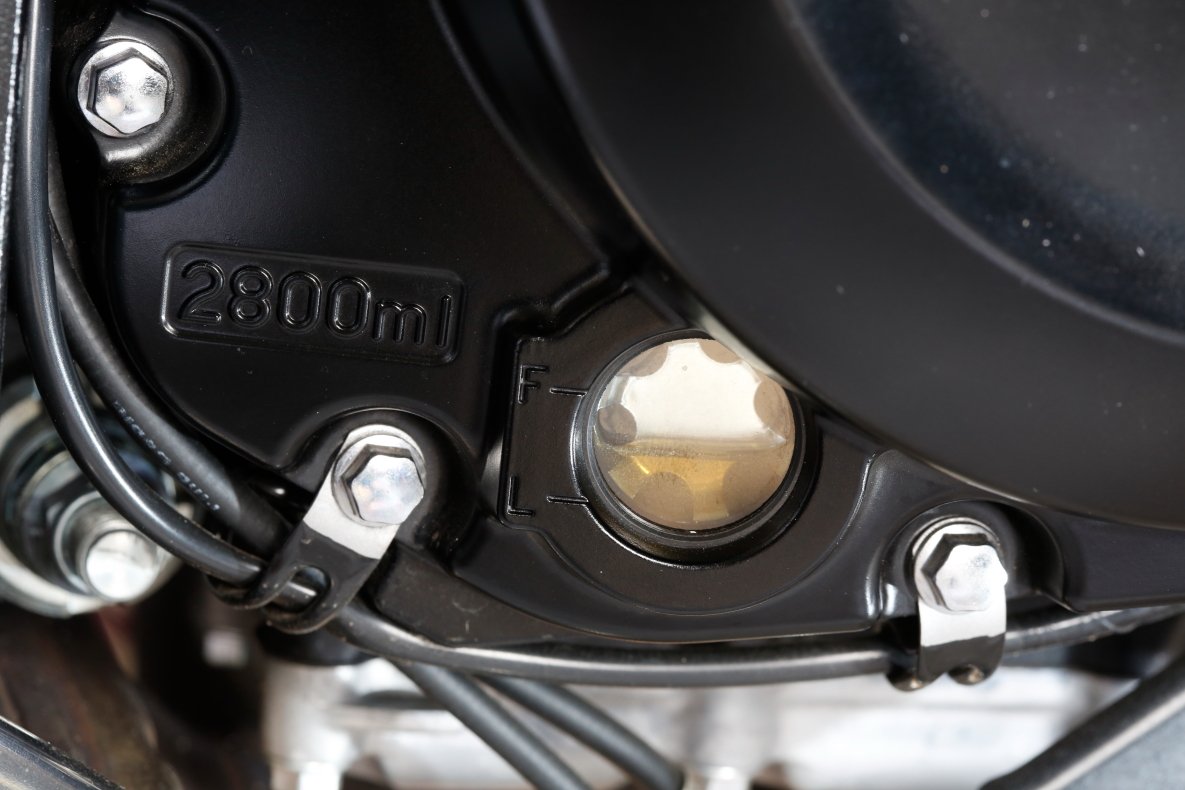 On the side stand, since the apparent oil level drops and is not correct, lean the vehicle to the left, and keep the motorcycle upright when checking the oil engine inspection window.